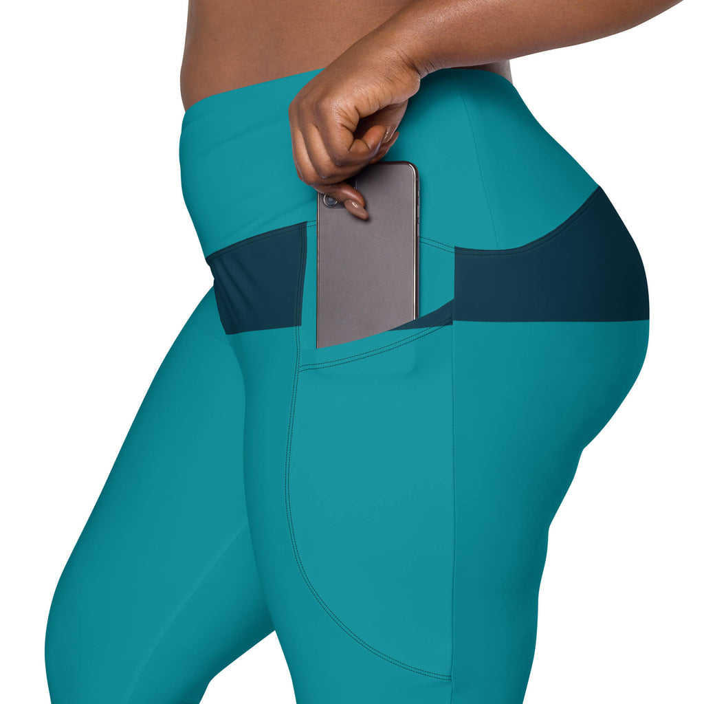 Smartphone in der Seitentasche der türkisfarbenen High-Waist-Leggings.